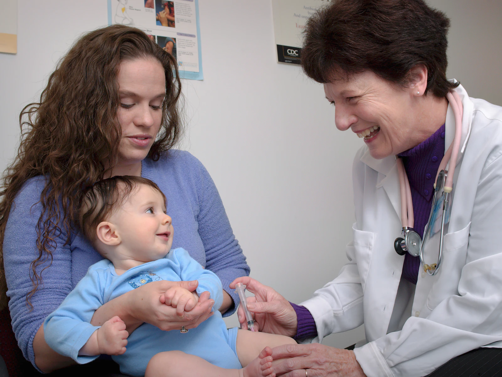 Doctor examining a toddler held by their mother
