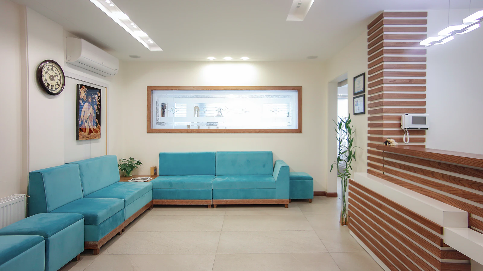 Bright waiting room with turquoise sofas and a wood-slat reception desk
